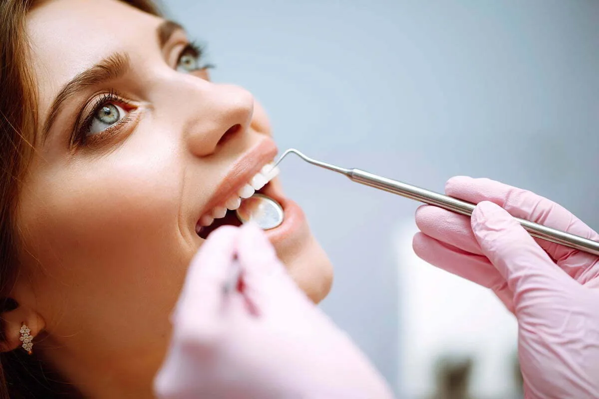 dentysta bada zęby lusterkiem i zgłębnikiem