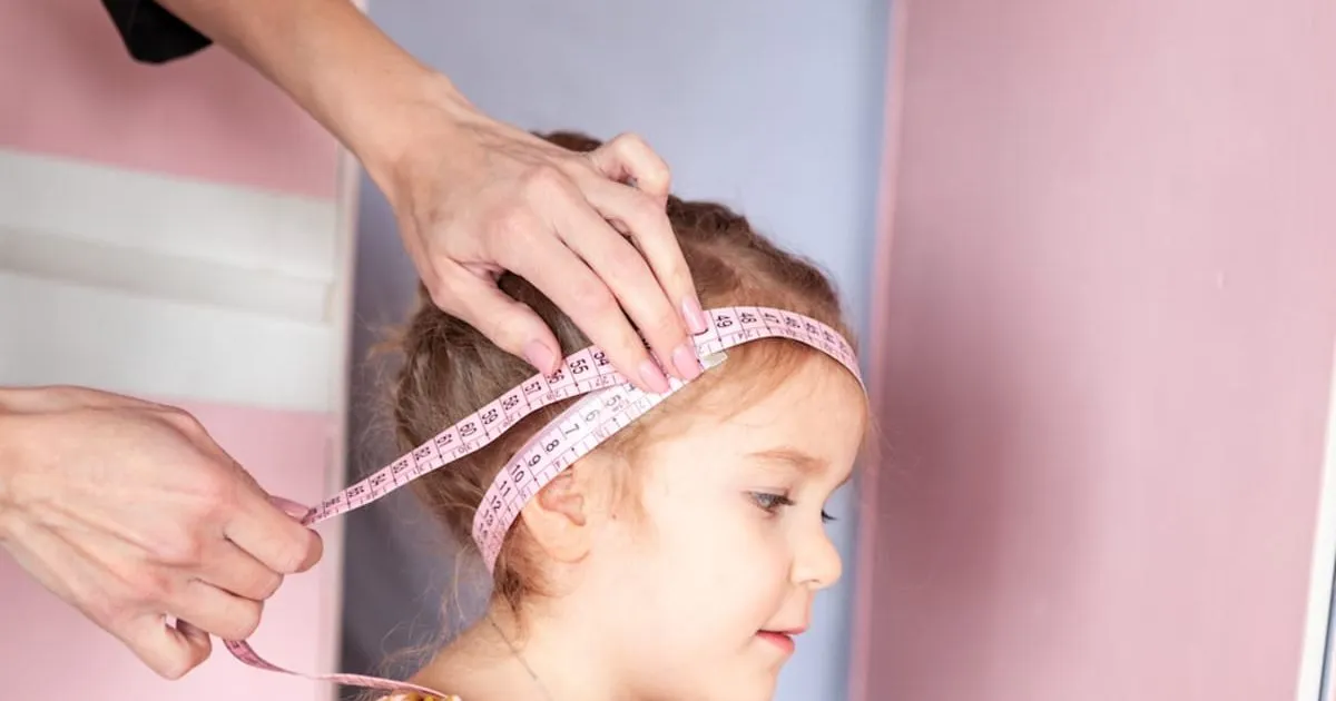 rodzic mierzący obw&oacute;d głowy dziecka
