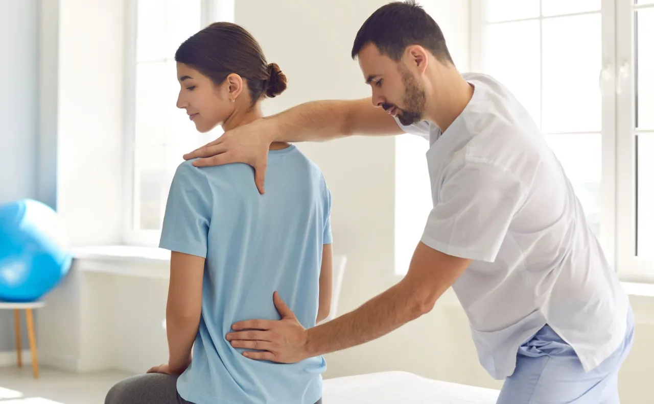 fizjoterapeuta pomaga pacjentowi wstawać po operacji kręgosłupa