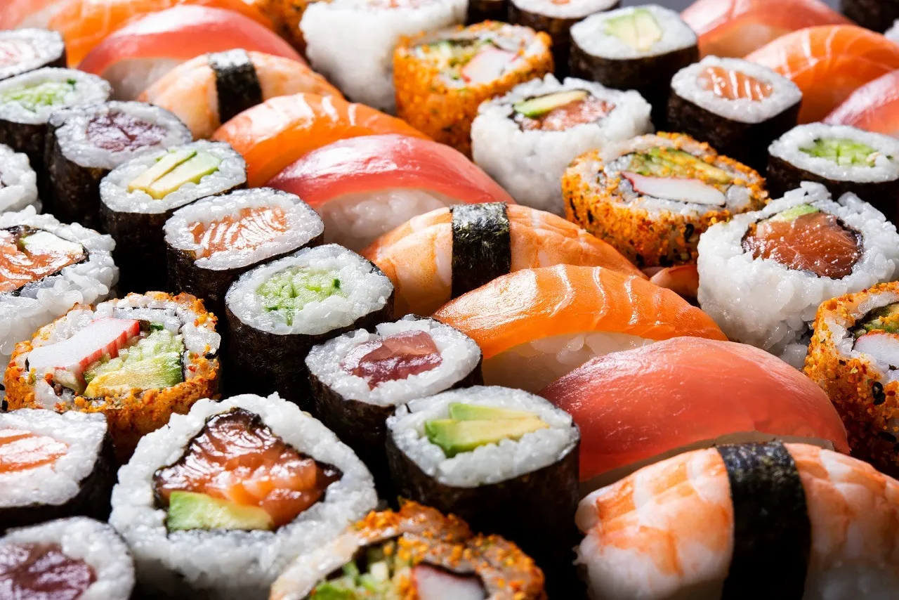 Różne rodzaje sushi: nigiri z łososiem, tuńczykiem i krewetką, maki z ogórkiem, awokado i paluszkami krabowymi.