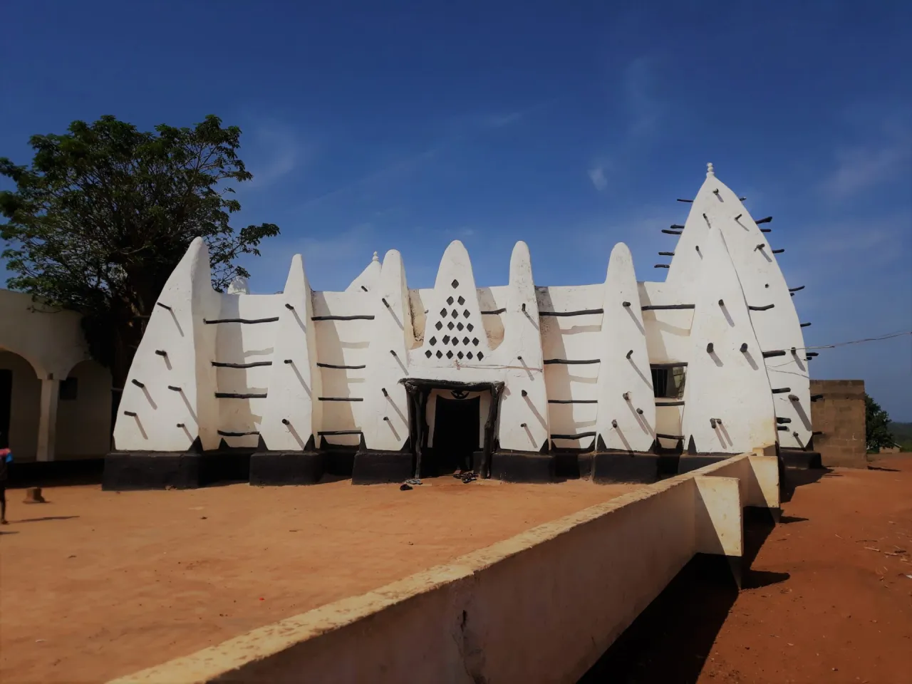 Tradycyjny meczet w Ghanie, z charakterystyczną białą architekturą i czarnymi zdobieniami. Odpowiedź na pytanie: czy Ghana jest bezpieczna? Tak, podróżowanie po Ghanie jest bezpieczne.