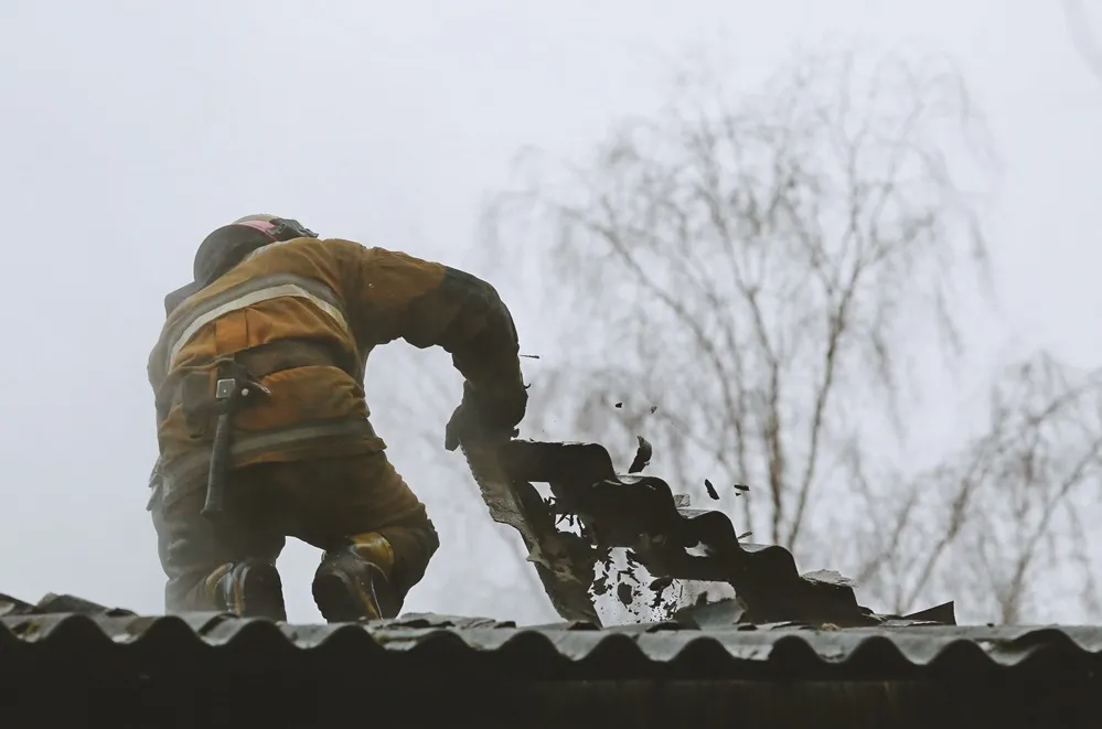 dekarz pracujący w trudnych warunkach pogodowych słońce lub deszcz