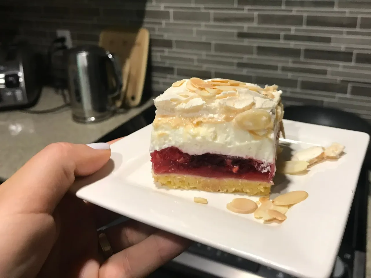 Pyszny kawałek ciasta z malinową chmurką, posypany płatkami migdałów. Czy malinową chmurkę można mrozić?