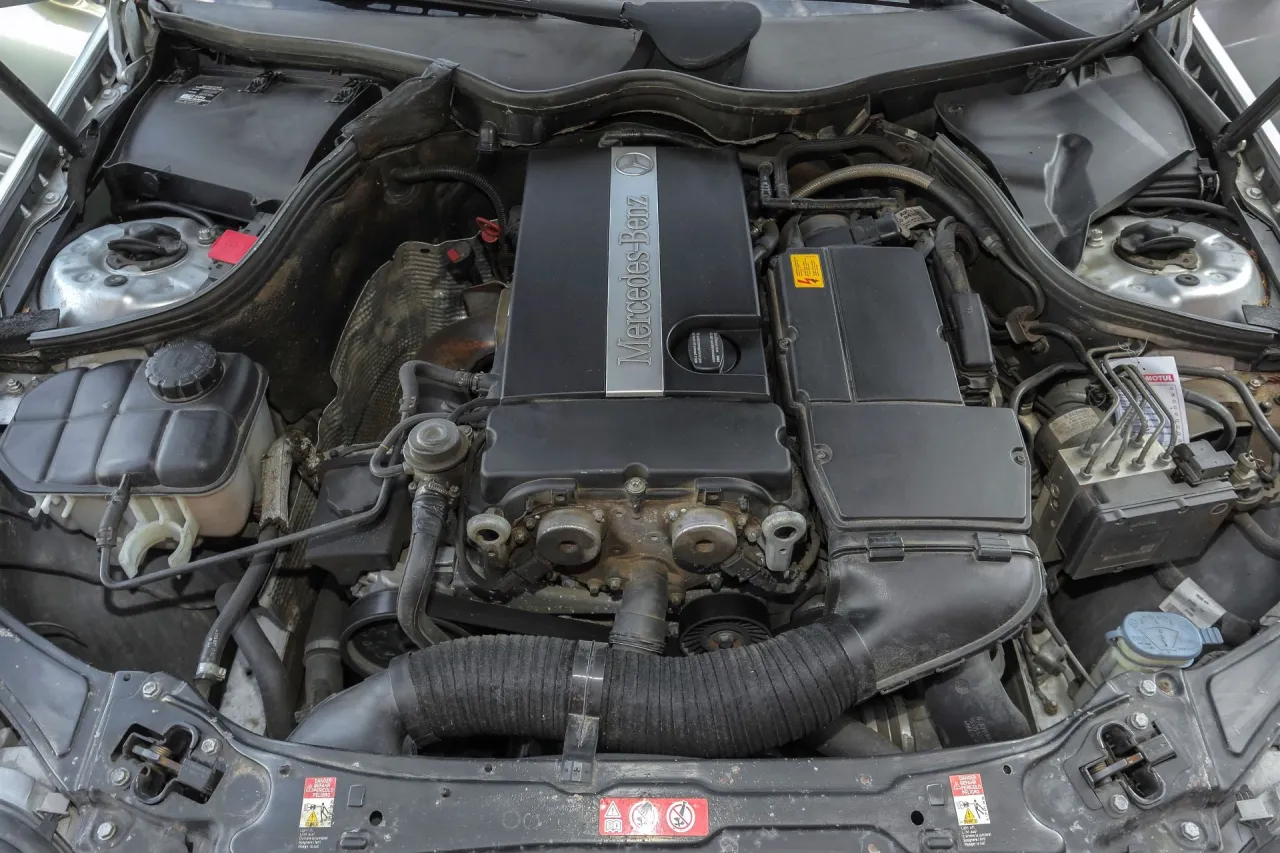 Silnik Mercedes W203 1.8 Kompressor. Widoczny osprzęt, przewody i osłona silnika z logo producenta.