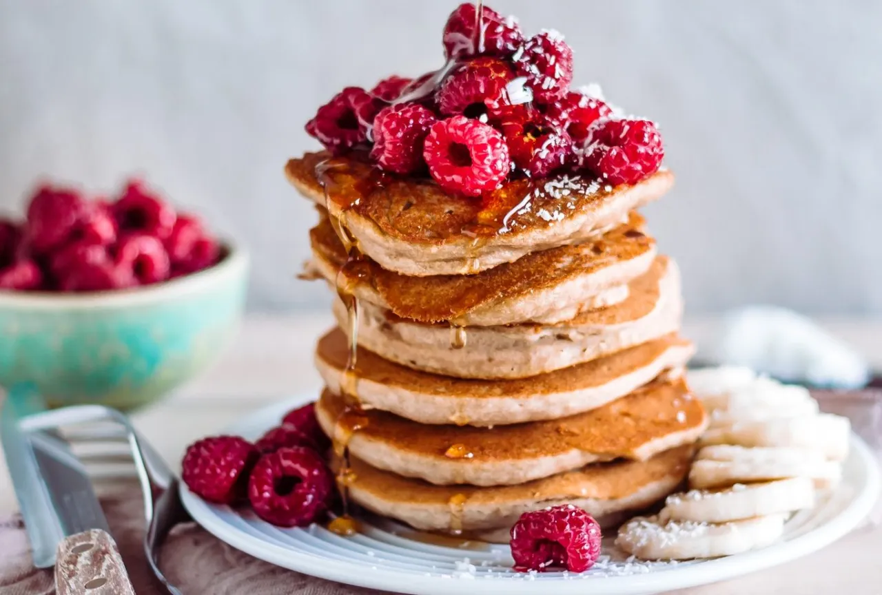 Pyszny stos zdrowych pancakes z malinami i syropem. Idealny przepis na zdrowe śniadanie.