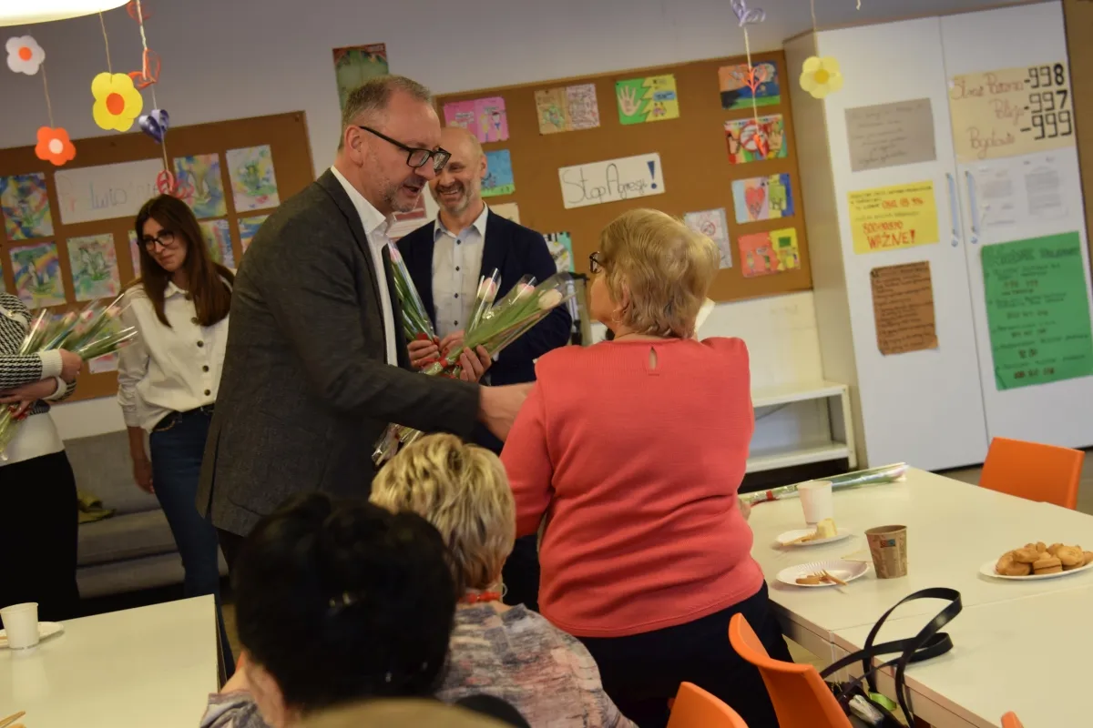 Kobieta uśmiecha się, odbierając komplement, z tłem miejskim lub kawiarnianym