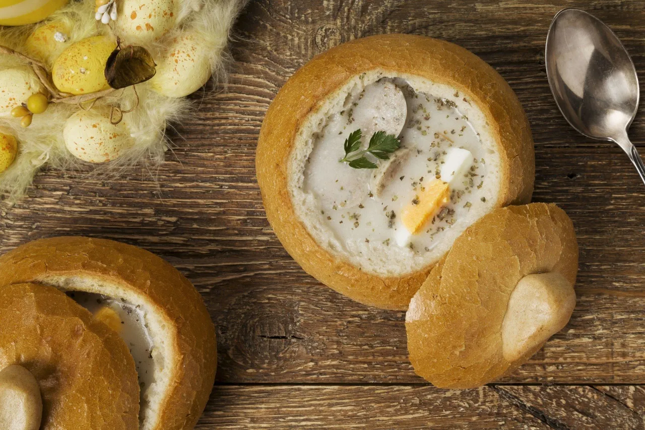 Tradycyjne co na obiad na Wielkanoc: żurek w chlebie z jajkiem i kiełbasą, obok pisanki.