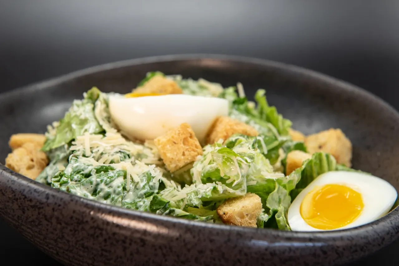 Kobieta dodająca starty parmezan do sałatki