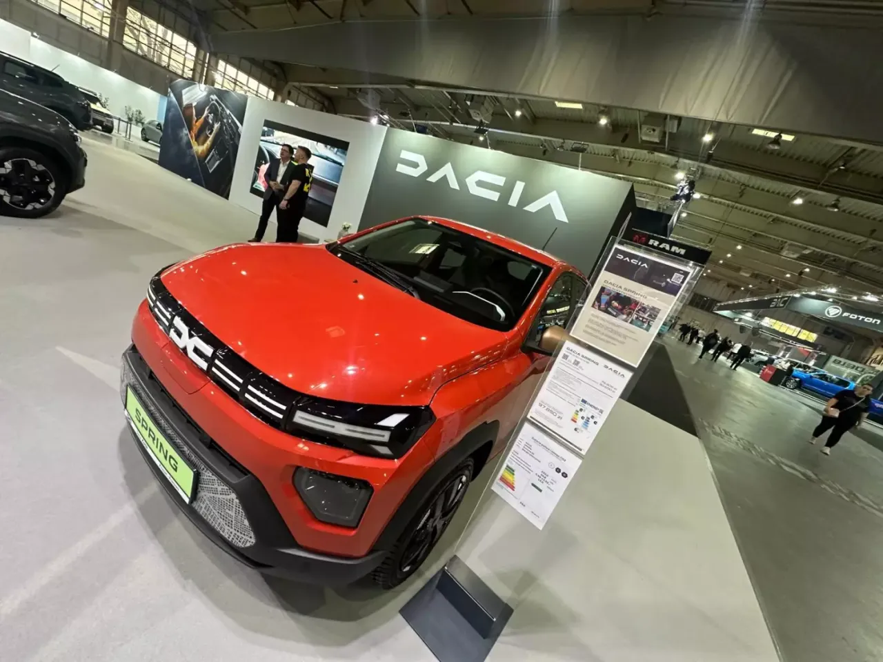 Czerwona Dacia Spring na targach motoryzacyjnych. Nowoczesny design i ekologiczne rozwiązania na rynku samochodowym.