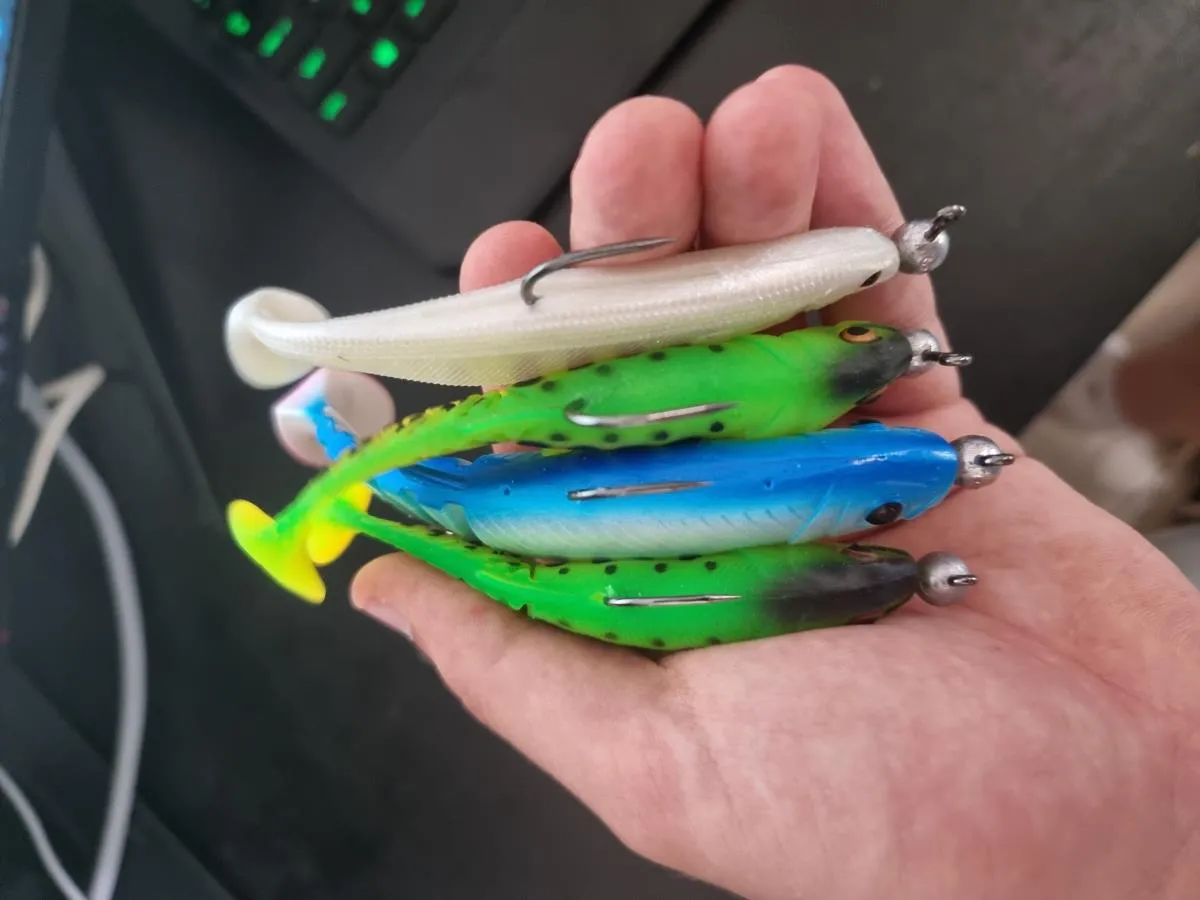 Kolorowe gumowe przynęty wędkarskie w dłoni, gotowe do łowienia ryb.