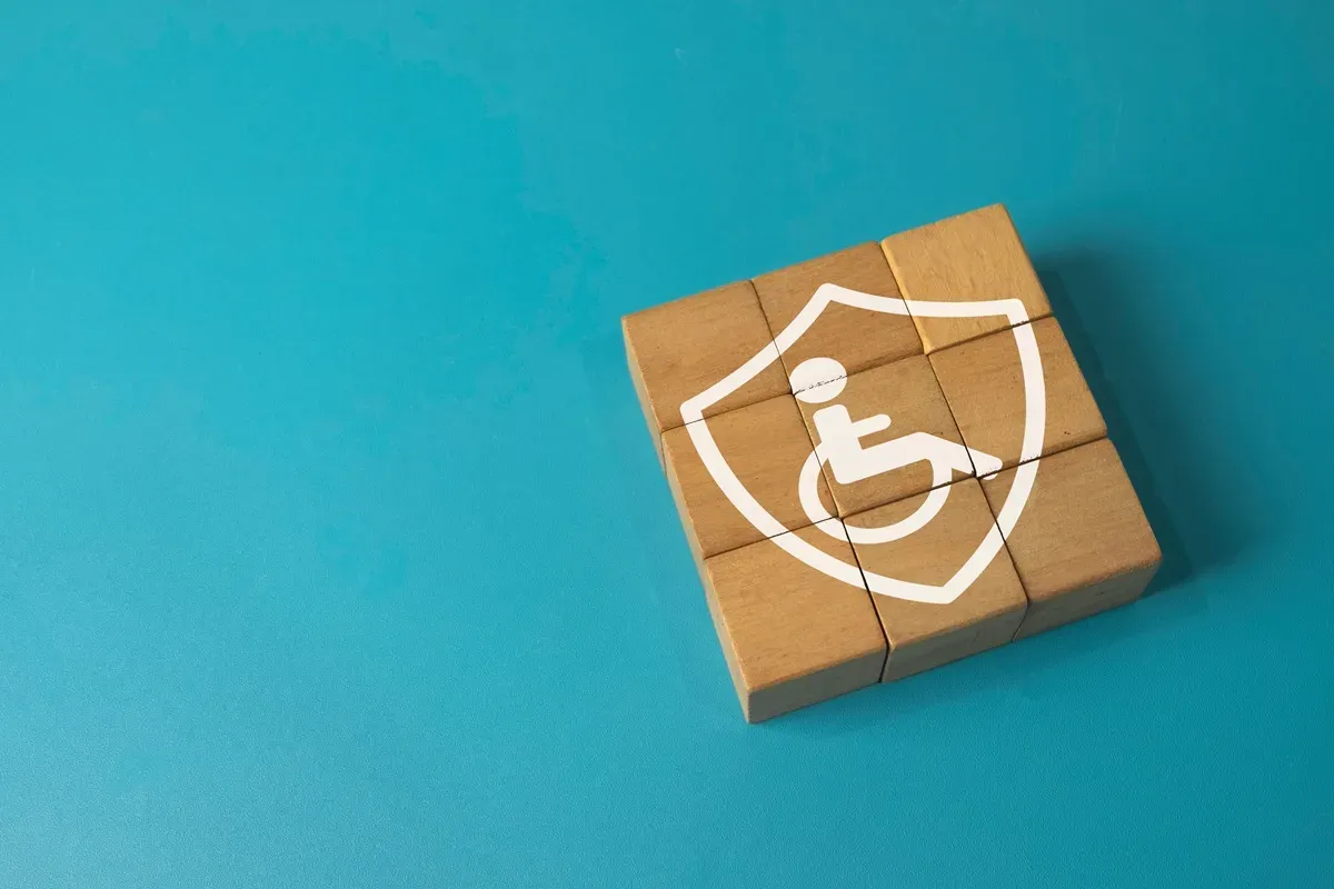 Drewniane klocki tworzą tarczę z symbolem osoby na wózku. Symbolizuje to wsparcie i ochronę, jakie przysługują osobie z orzeczeniem umiarkowanym.
