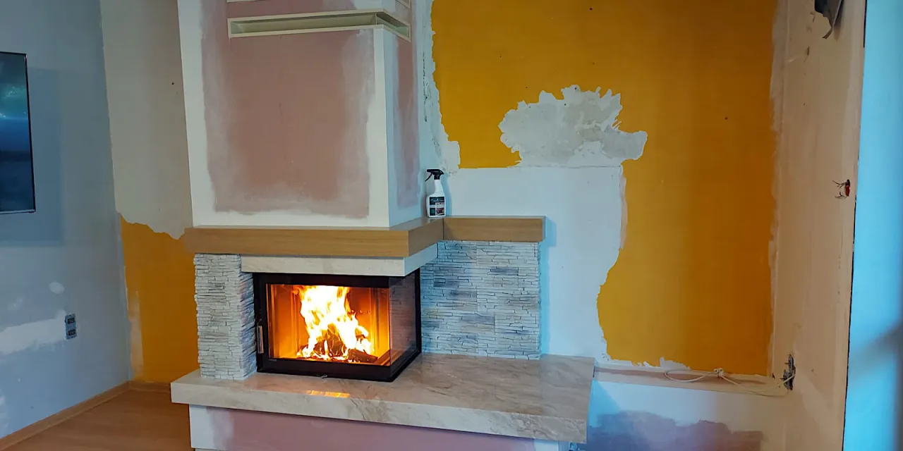 Zabudowa kominka instrukcja: płonący ogień w nowoczesnym kominku z kamienną okładziną, w trakcie remontu pomieszczenia.