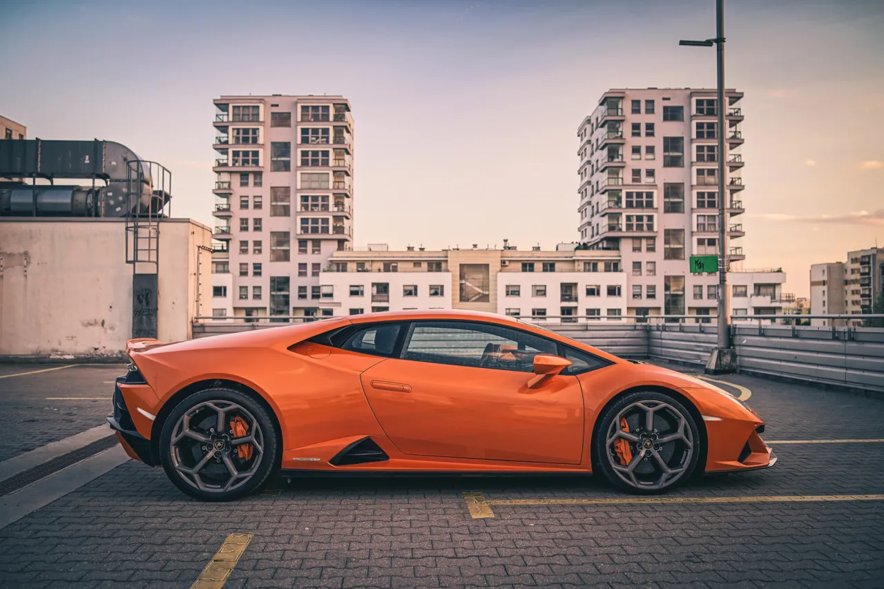 Pomarańczowe Lamborghini na parkingu. Zastanawiasz się, ile kosztuje wypożyczenie lamborghini na weekend?
