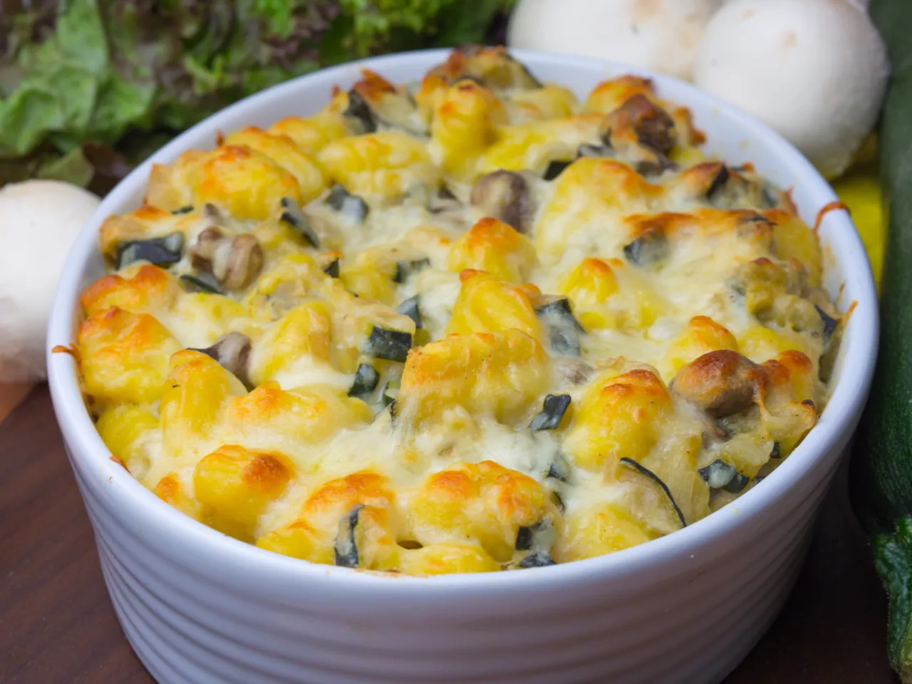 Zapiekane gnocchi z cukinią i pieczarkami, polane ciągnącym się serem. Pyszne danie główne.