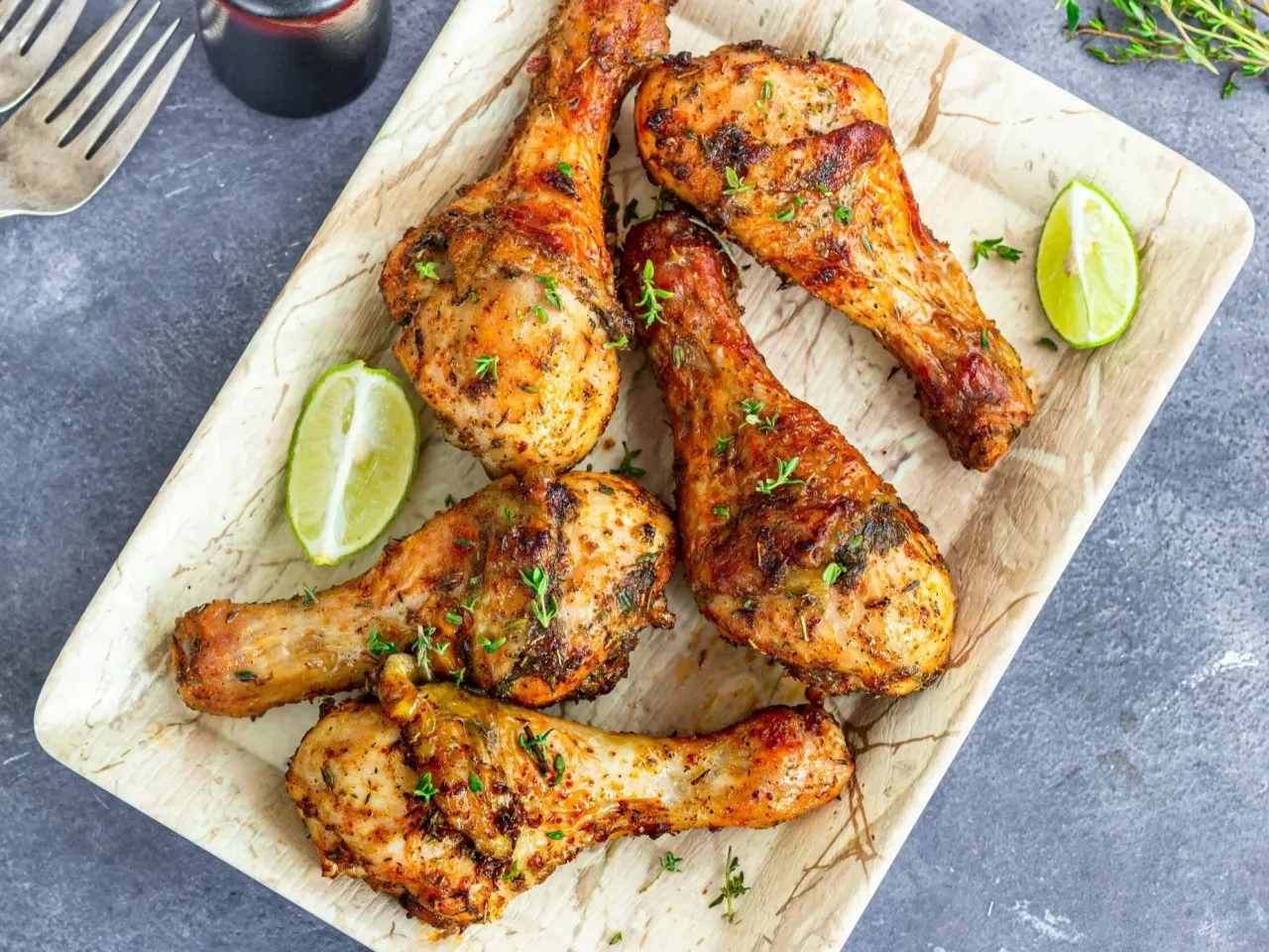 Pięć soczystych pałek z kurczaka, pieczonych z ziołami i podanych z ćwiartkami limonki.