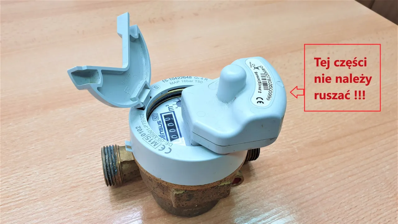 Wodomierz z otwartą klapką i czerwoną ramką z napisem