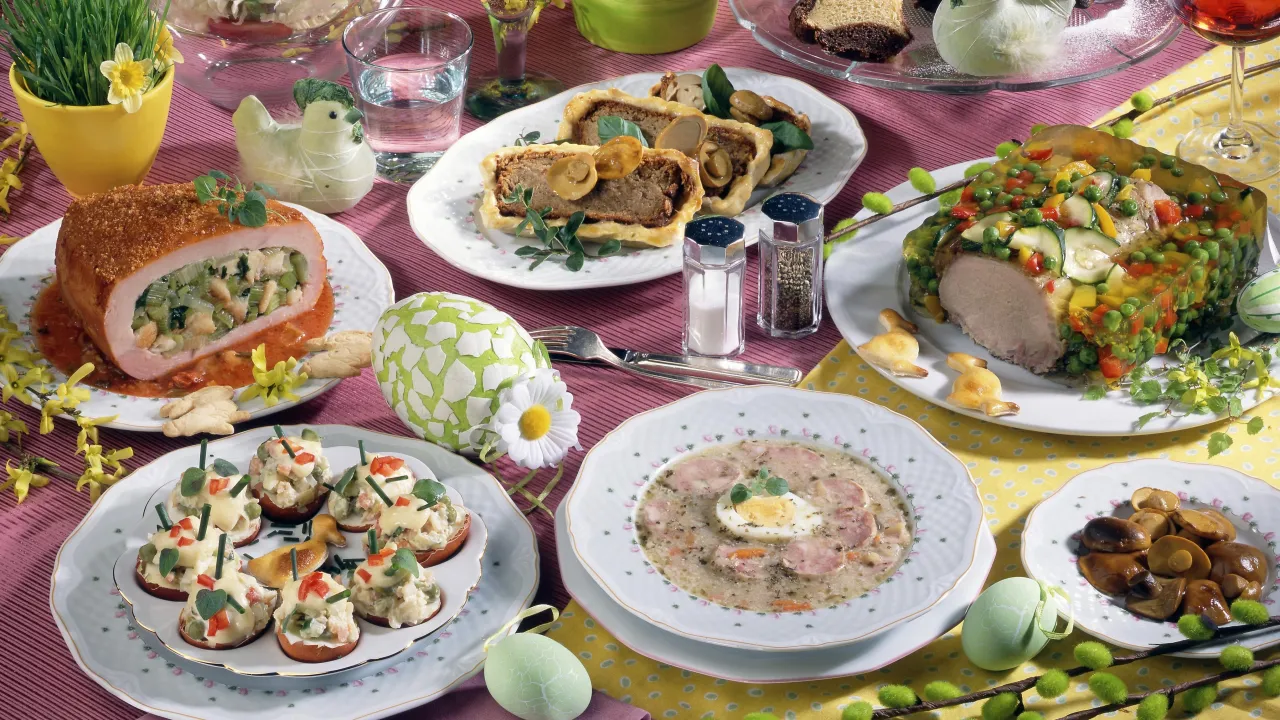 Wielkanocny st&oacute;ł pełen pyszności: pieczony schab, galareta z warzywami, pasztet, jajka faszerowane i żurek. Idealne inspiracje, co ugotować na święta.