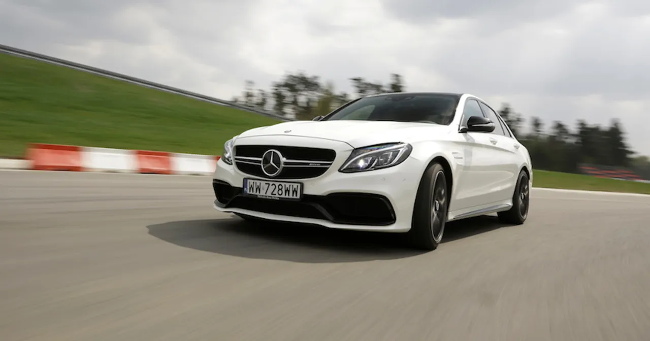 Biały Mercedes-AMG C63 Coupe pędzi po torze wyścigowym, zostawiając za sobą rozmyte tło.