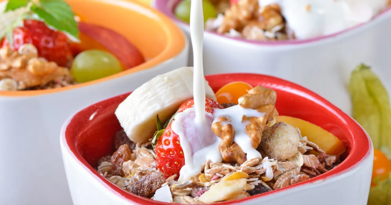 Pyszne śniadanie przed czy po treningu? Mleko spływa na musli z owocami i orzechami.