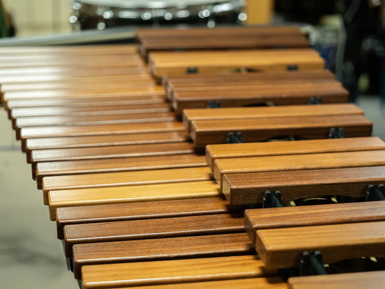 Drewniane, błyszczące listewki instrumentów perkusyjnych niemelodycznych ułożone w rzędy, gotowe do wydobycia dźwięków.