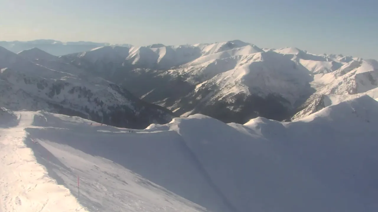 Widok z kamery na Kasprowy Wierch w Zakopanem. Ośnieżone szczyty Tatr i trasa narciarska.