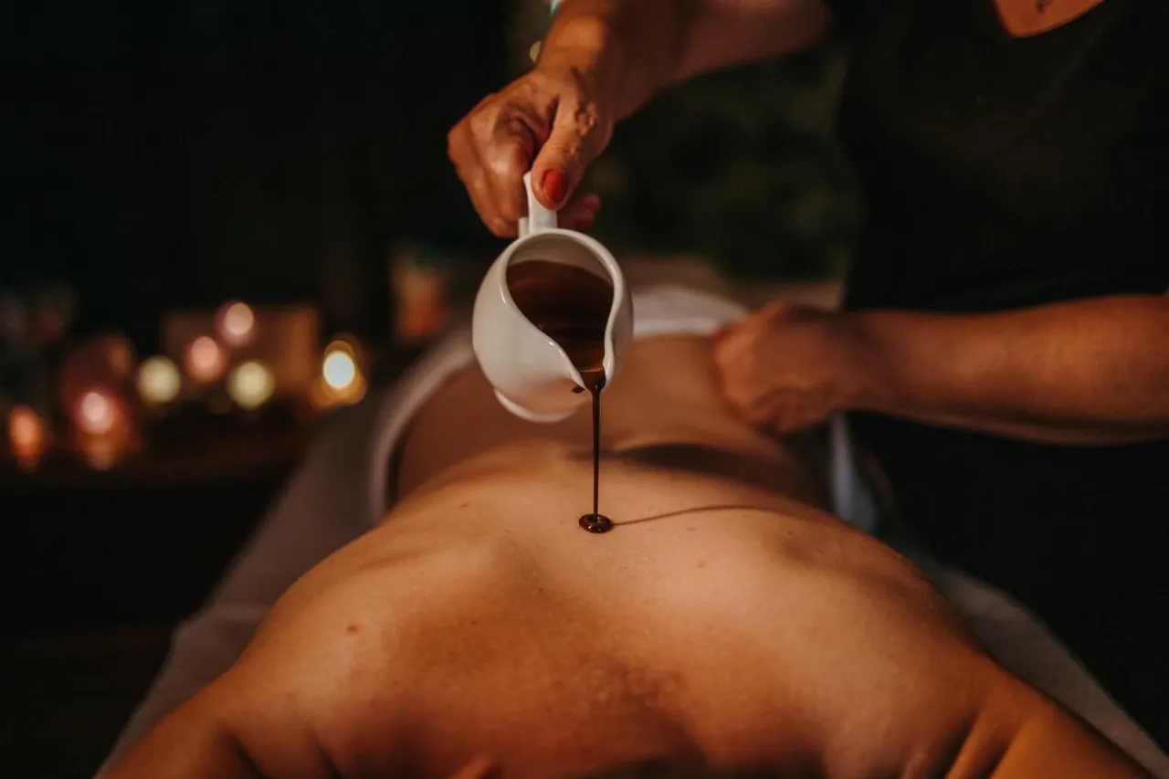Ciepła czekolada do masażu spa spływa na plecy, tworząc relaksującą atmosferę.
