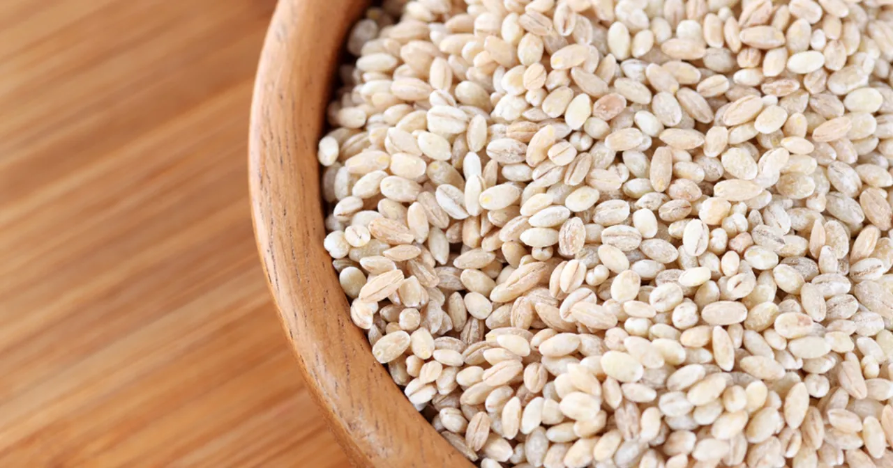 Kasza jęczmienna w drewnianej misce. Zastanawiasz się, ile wody na szklankę kaszy jęczmiennej? Oto odpowiedź w postaci zbliżenia na ziarna.