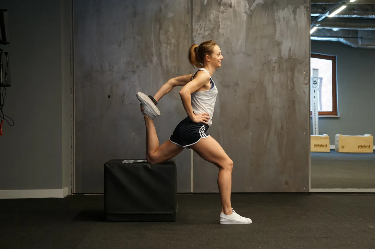 Biegacz rozciągający mięśnie czworogłowe uda po biegu