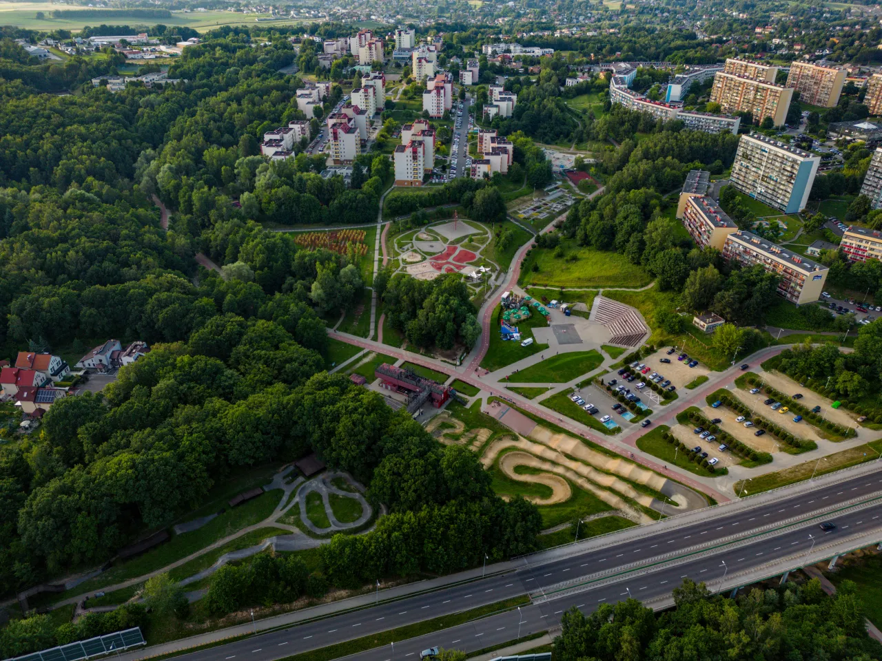 Widok z lotu ptaka na rodzinny park rozrywki Trzy Wzgórza, otoczony zielenią i osiedlami mieszkaniowymi.
