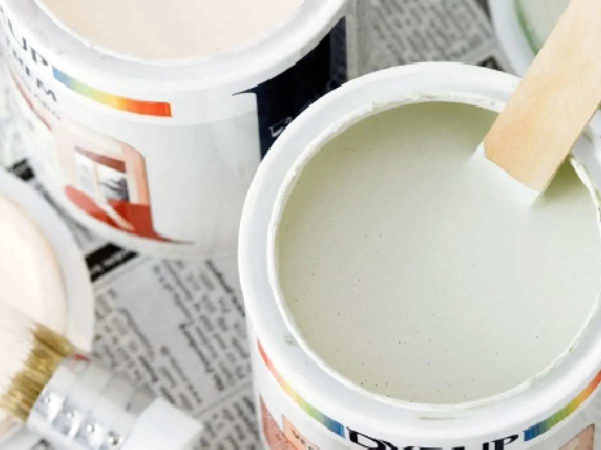 Puszki z farbą i pędzel. Przygotowanie do malowania ścian, czyli jak zrobić grunt do ścian.