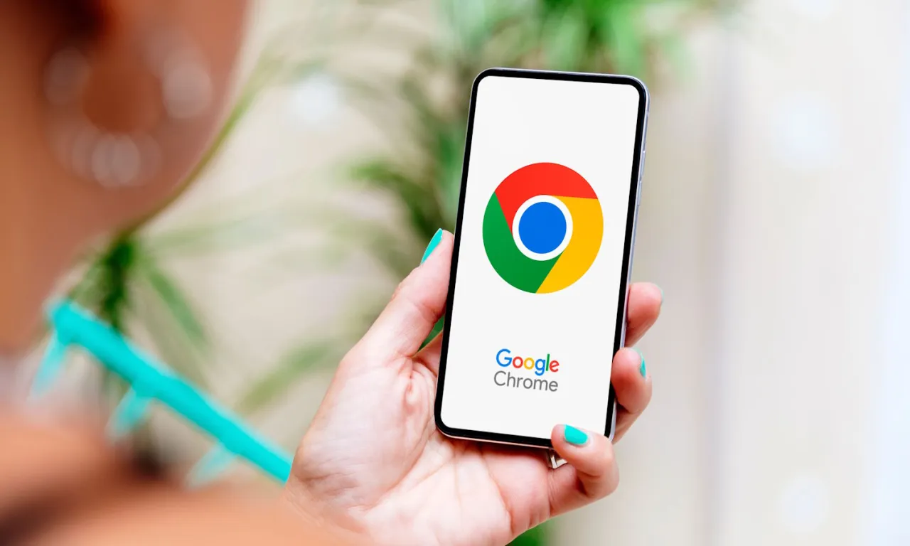 Dłoń trzyma smartfon z logo Google Chrome. Dowiedz się, jak zaktualizować przeglądarkę Chrome, aby korzystać z najnowszych funkcji i zabezpieczeń.