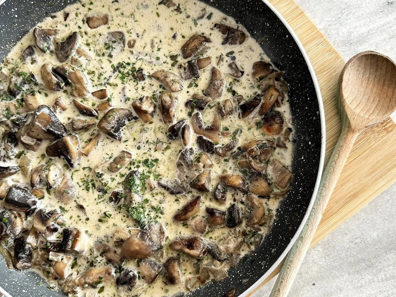 Kremowy sos z pieczarek na patelni, posypany natką pietruszki. Idealny przepis, jak zrobić dobry sos z pieczarek.