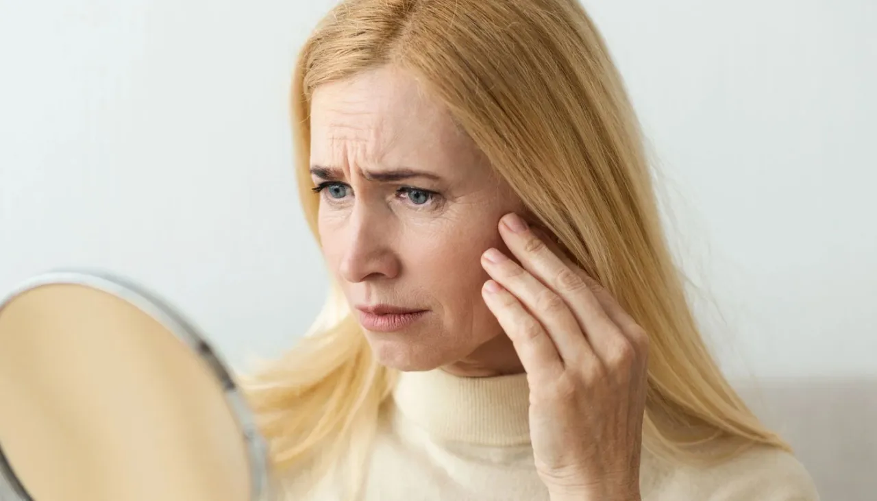 Kobieta z niepokojem ogląda swoją cerę po rzuceniu palenia, zauważając zmarszczki.