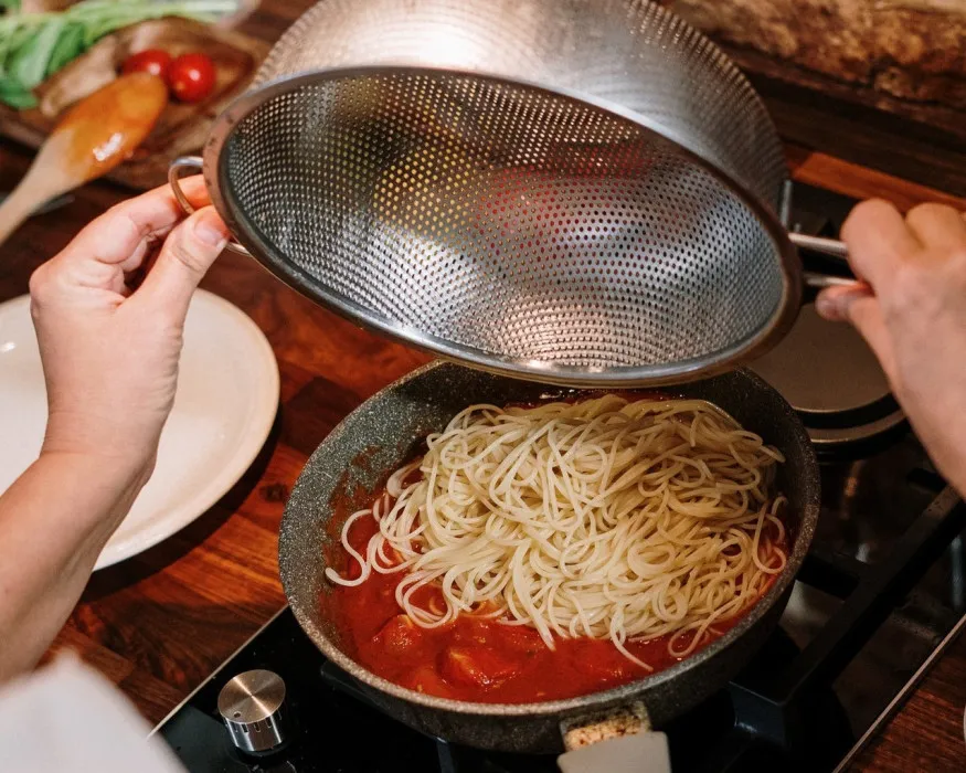 Makaron odcedzony w durszlaku z parującą wodą