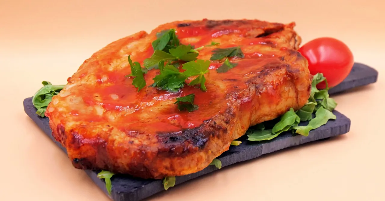 Soczysta kark&oacute;wka z sosem sojowym i ketchupem, udekorowana natką pietruszki i pomidorkiem, podana na ciemnej desce z rukolą.