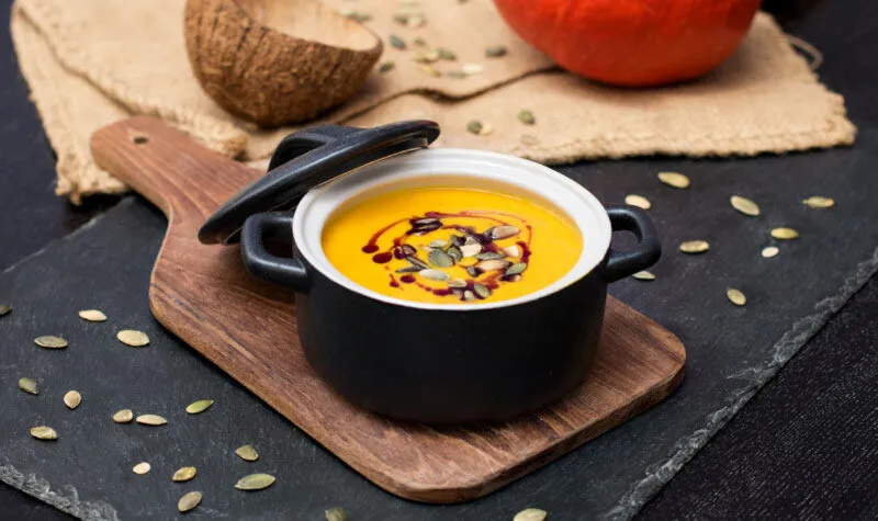 Cremige Kürbis-Curry-Suppe in einer Schale mit Toppings wie Kürbiskernen und Koriander