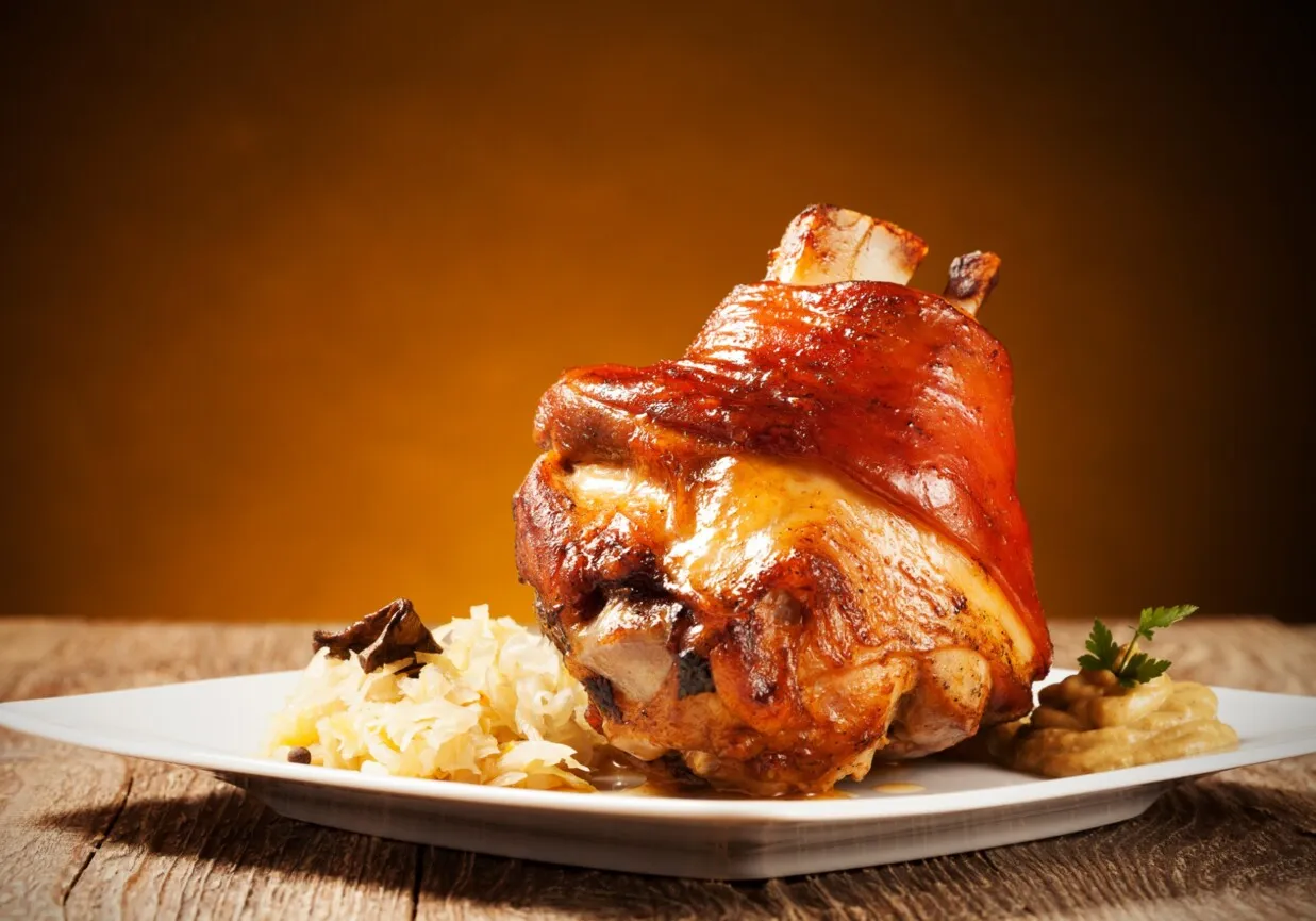 Soczysta, pieczona golonka z chrupiącą sk&oacute;rką, podana z kapustą i musztardą. Idealna na obiad, gdy wiesz, jak peklować golonkę.