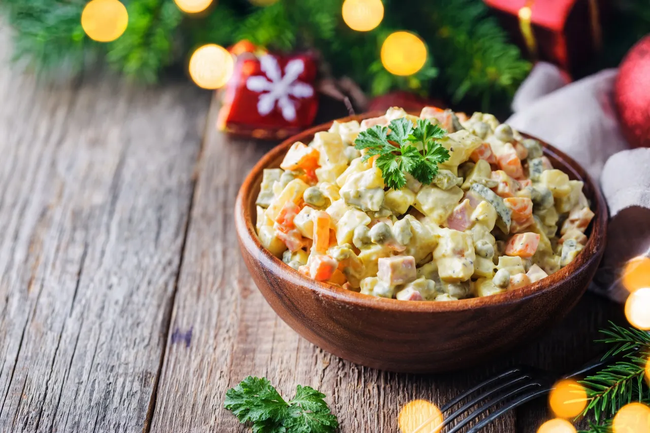 Sałatka jarzynowa z ziemniakami typu A odmiany, udekorowana natką pietruszki, na drewnianym stole, w świątecznej atmosferze.