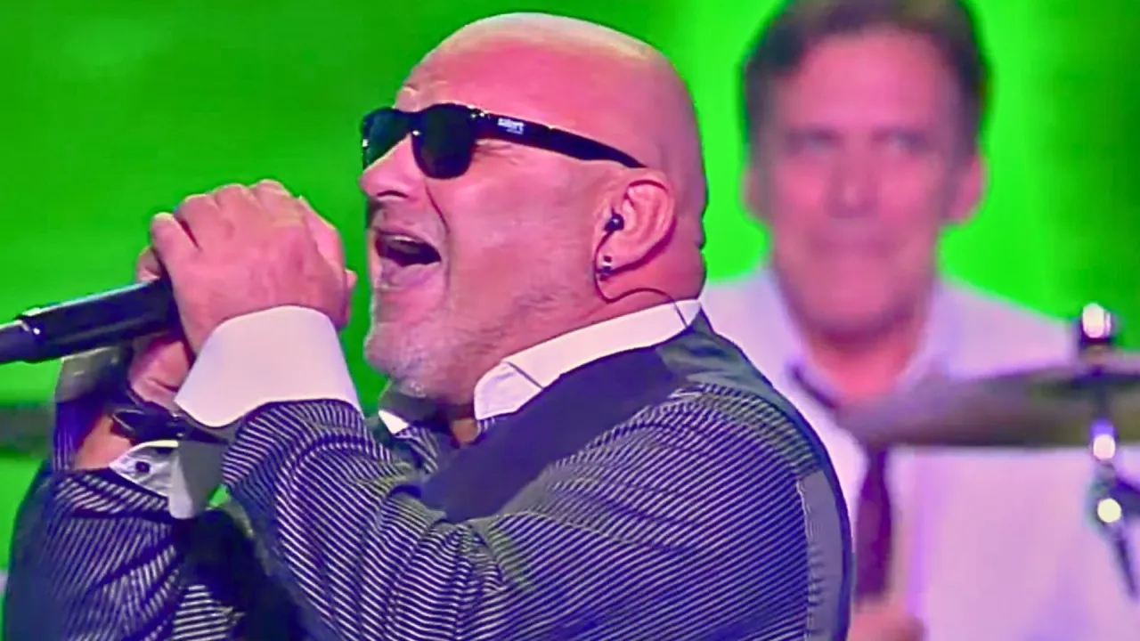 Charyzmatyczny wokalista w okularach przeciwsłonecznych śpiewa do mikrofonu, czując, że 