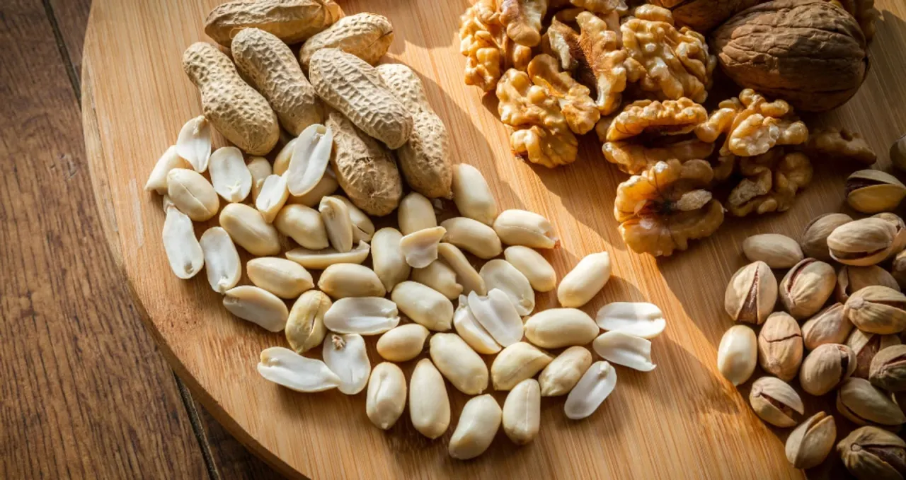 Orzeszki ziemne, orzechy włoskie i pistacje na desce. Czy pies może jeść orzeszki ziemne? Lepiej nie ryzykować.