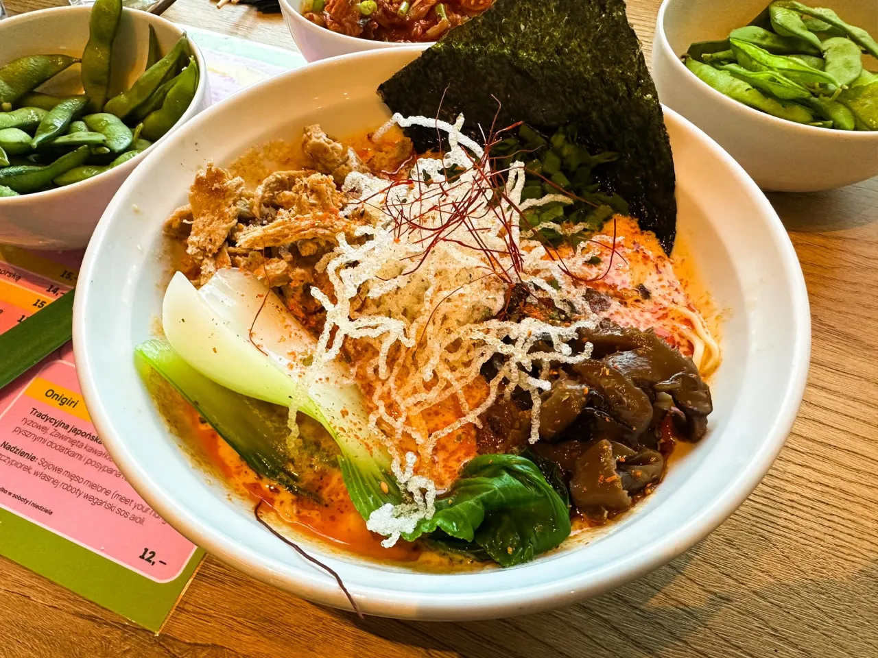 A miska pełna aromatycznego vege ramen z makaronem, warzywami, nori i chrupiącymi dodatkami.