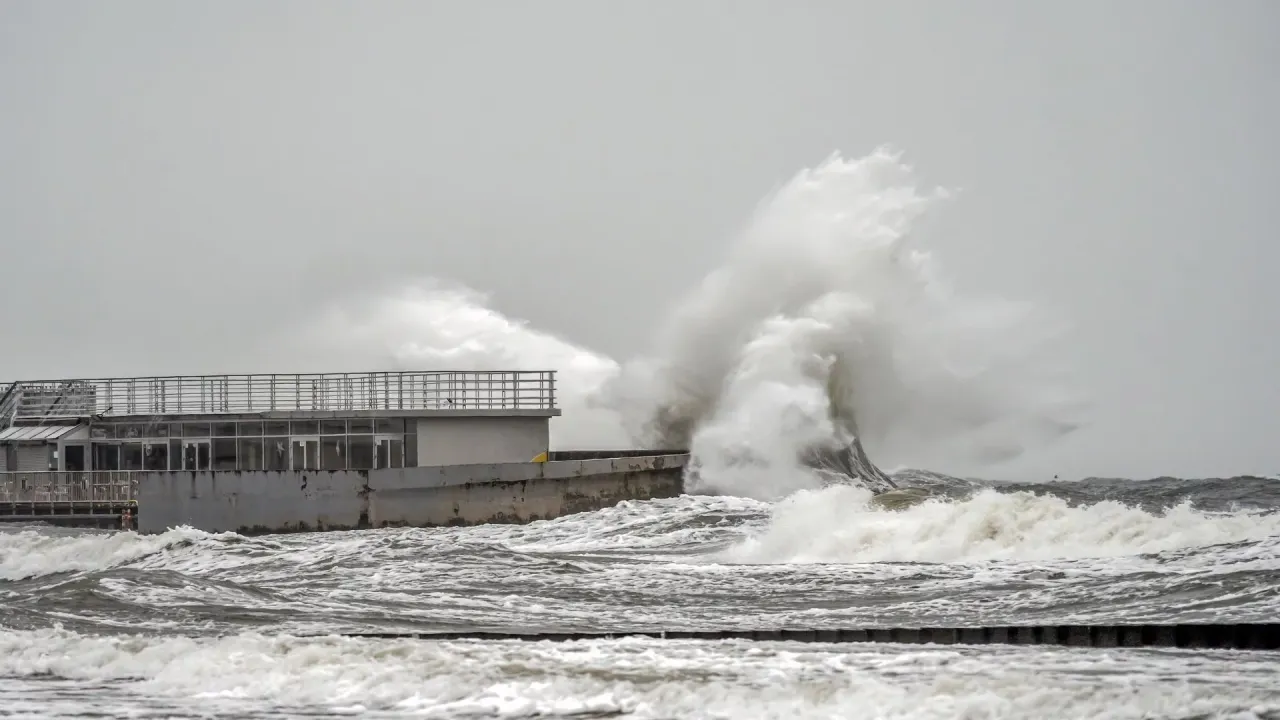 Potężne fale rozbijają się o brzeg, pokazując, kiedy będzie sztorm na Bałtyku. Budynek na nabrzeżu jest narażony na żywioł.