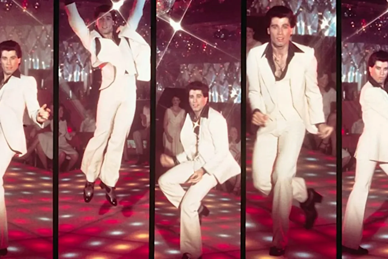John Travolta w białym garniturze tańczy na parkiecie, czuć gorączkę sobotniej nocy.