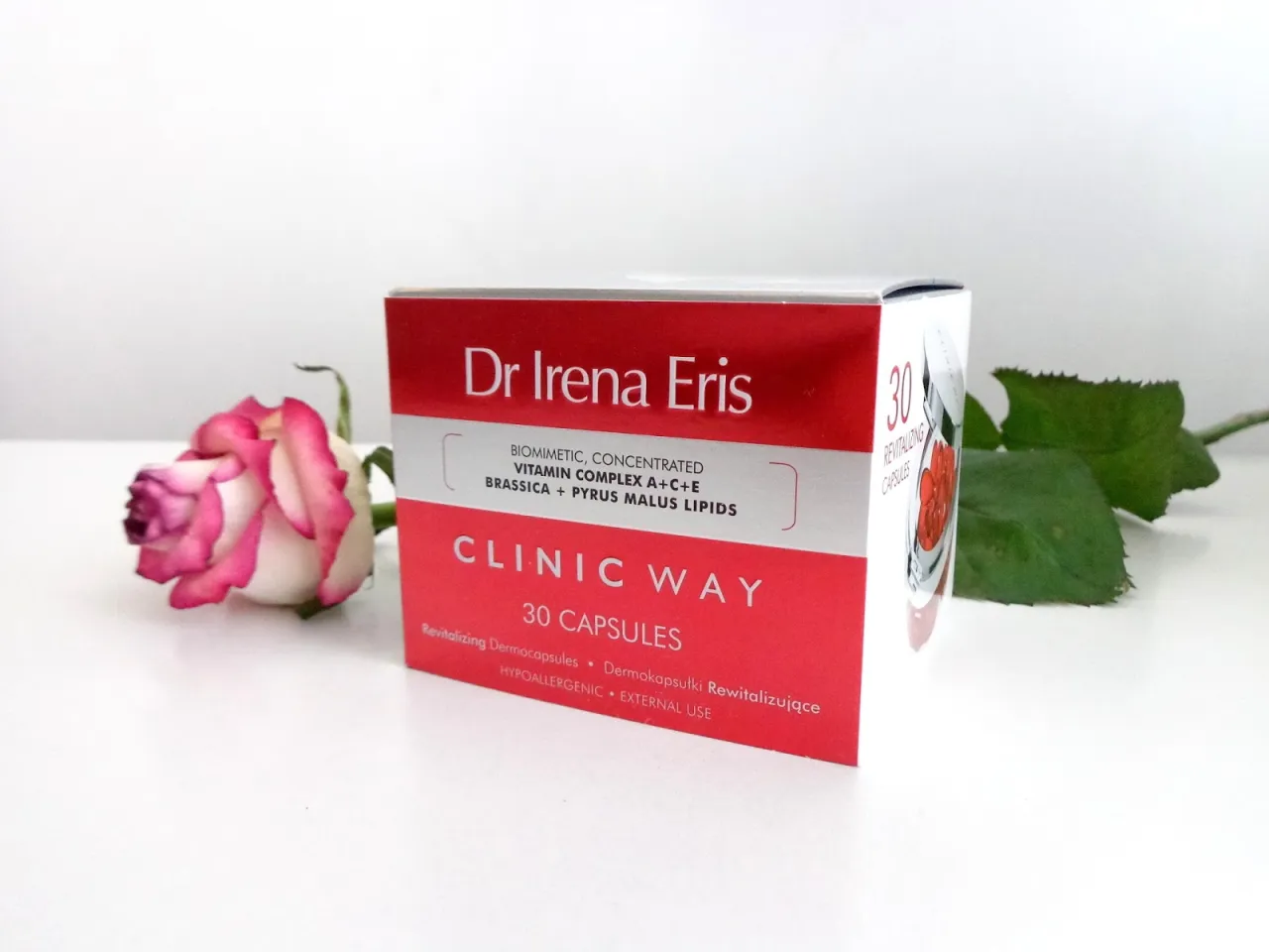 Dr Irena Eris Clinic Way Dermokapsułki Rewitalizujące, 30 kapsułek, obok pięknej r&oacute;ży.