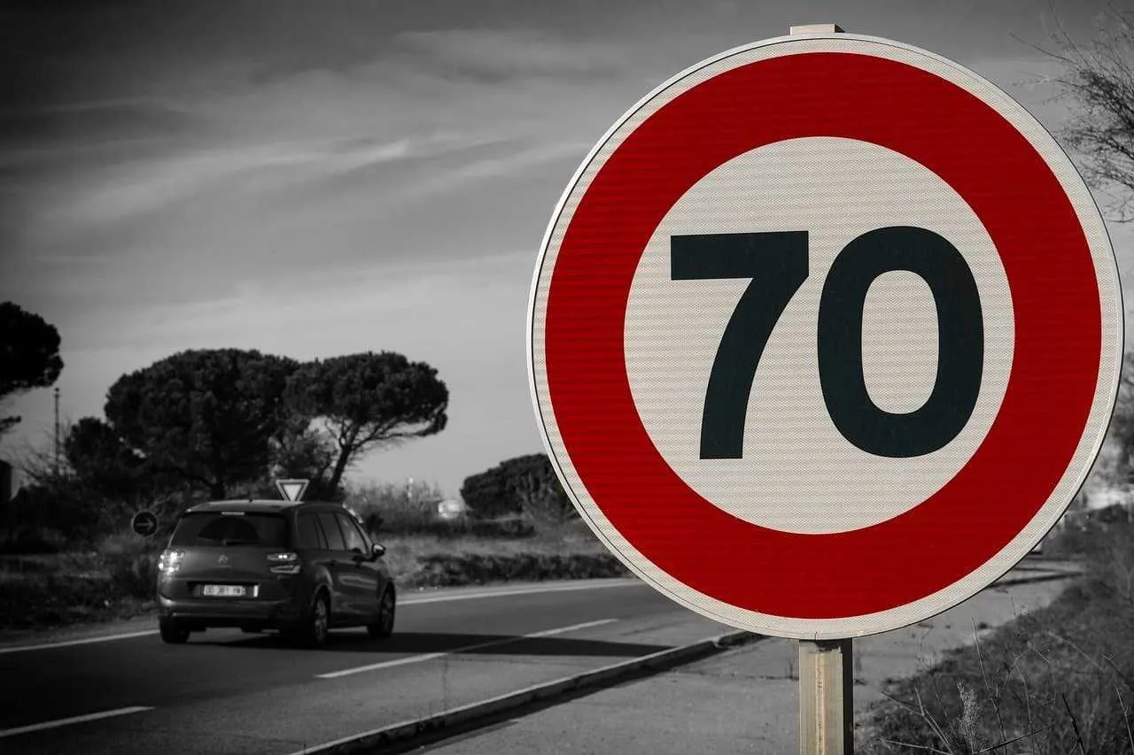 Znak ograniczenia prędkości do 70 km/h. Samoch&oacute;d jedzie drogą ekspresową, przestrzegając przepis&oacute;w.