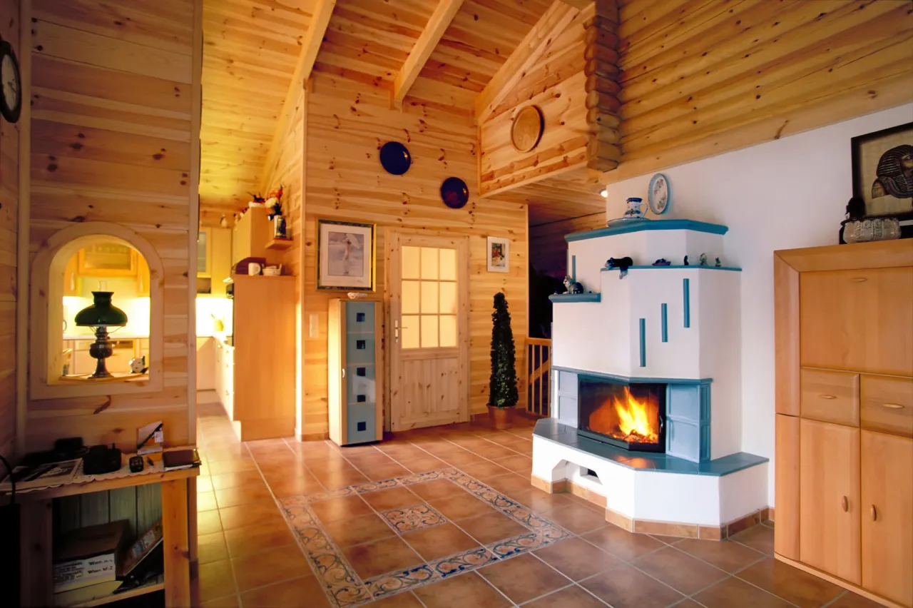 Wnętrze domu z bali, z kominkiem i kuchnią w tle. Wiele drewna na dom z bali, ciepło i przytulnie.