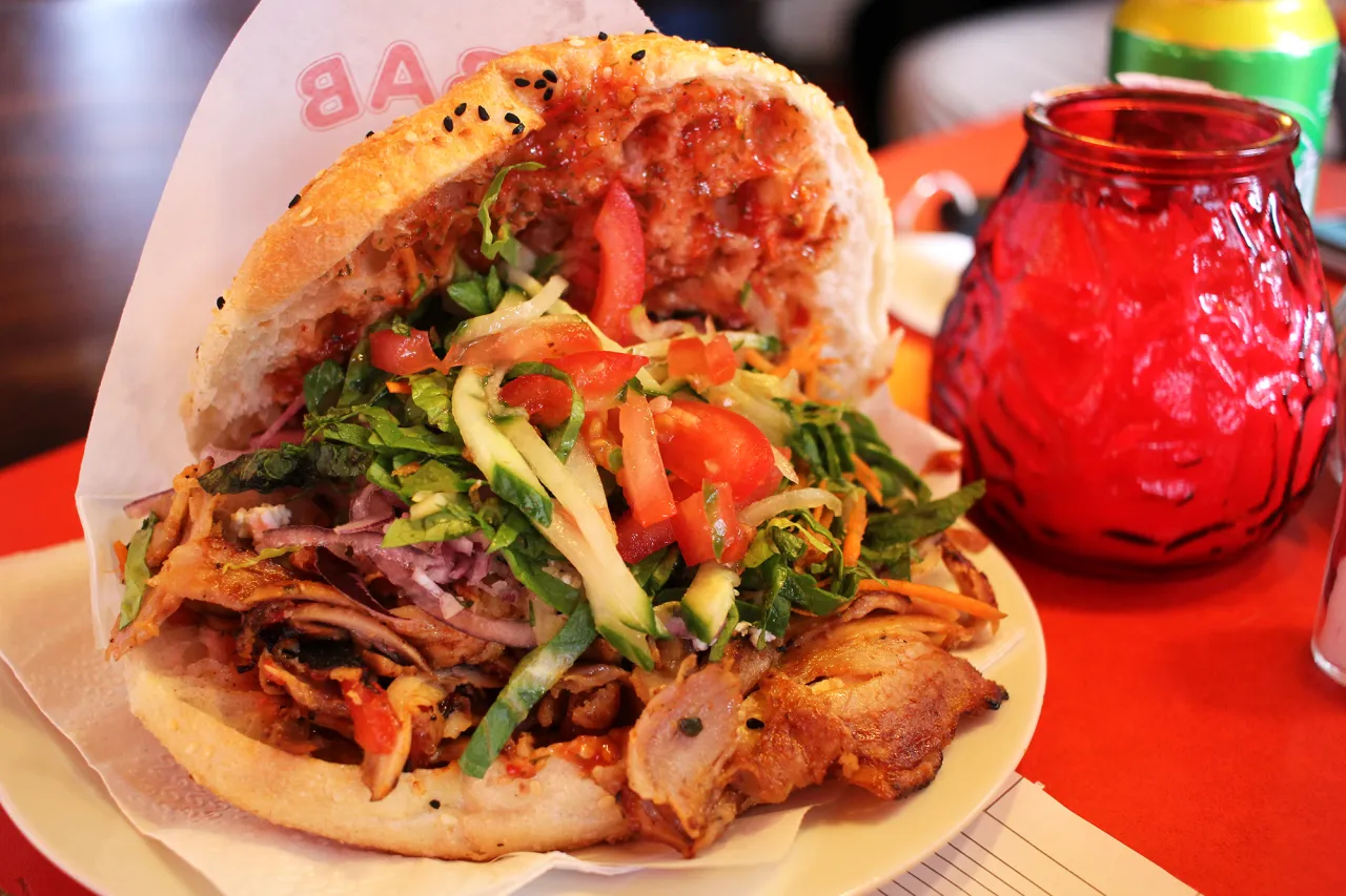 Pyszny kebab z mięsem, warzywami i sosem w bułce, przypominający o jego tureckich korzeniach.