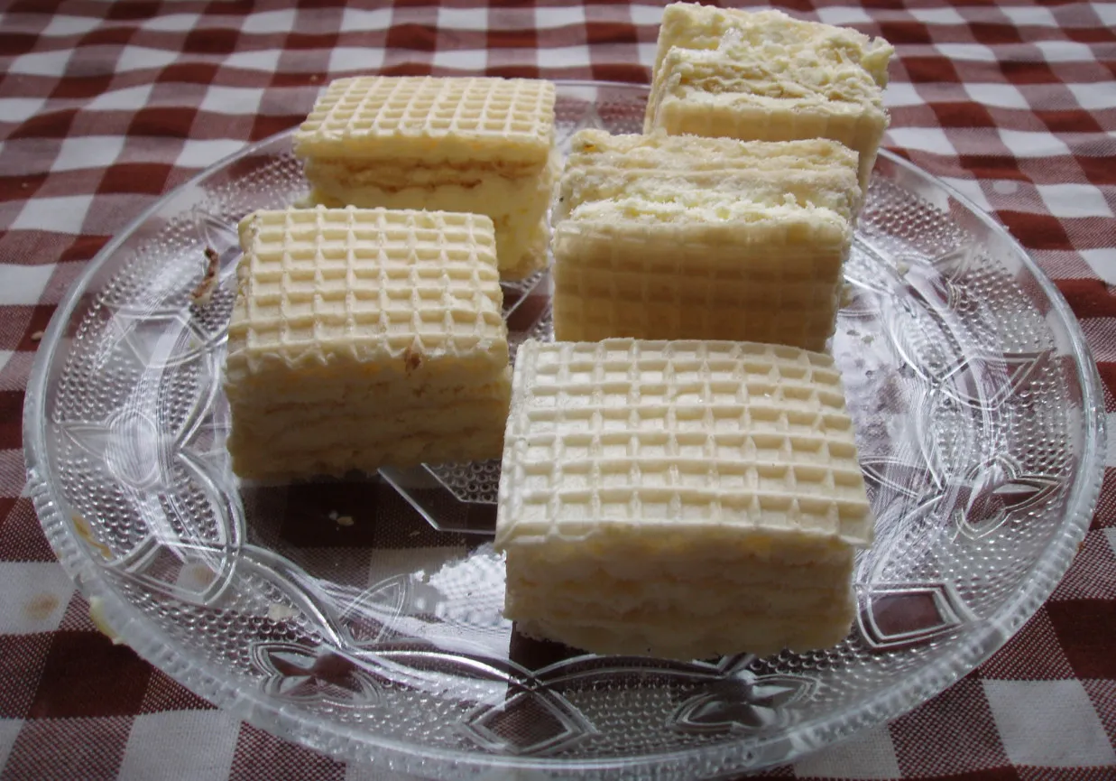 Sześć kwadratowych wafli przekładanych kremem, przypominających smak dzieciństwa i lody śnieżka z PRL-u, ułożone na szklanej paterze.
