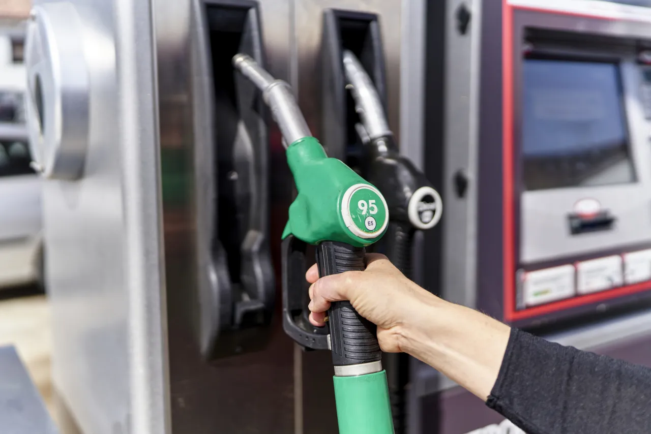 Dłoń trzyma zielony pistolet z oznaczeniem 95, obok czarny z 98. R&oacute;żnica między benzyną 95 a 98 to liczba oktanowa.
