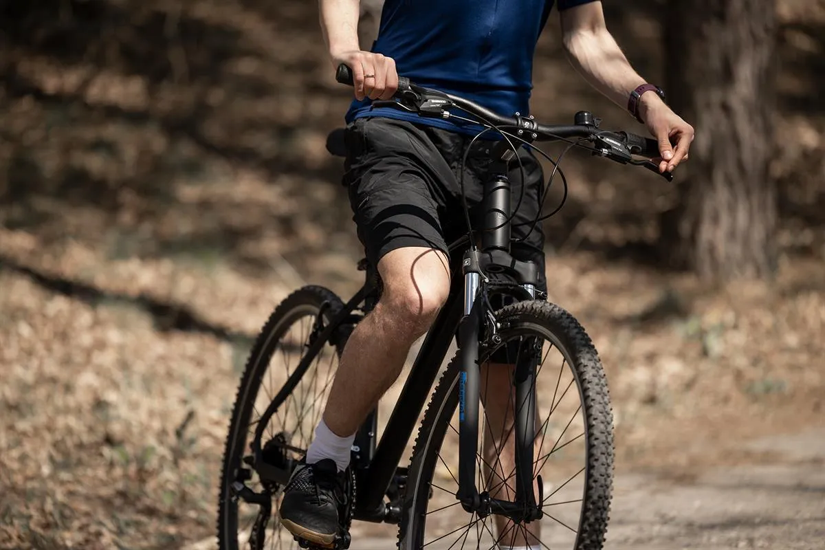 Mężczyzna na rowerze cross do 3000 zł, gotowy na leśną przejażdżkę.